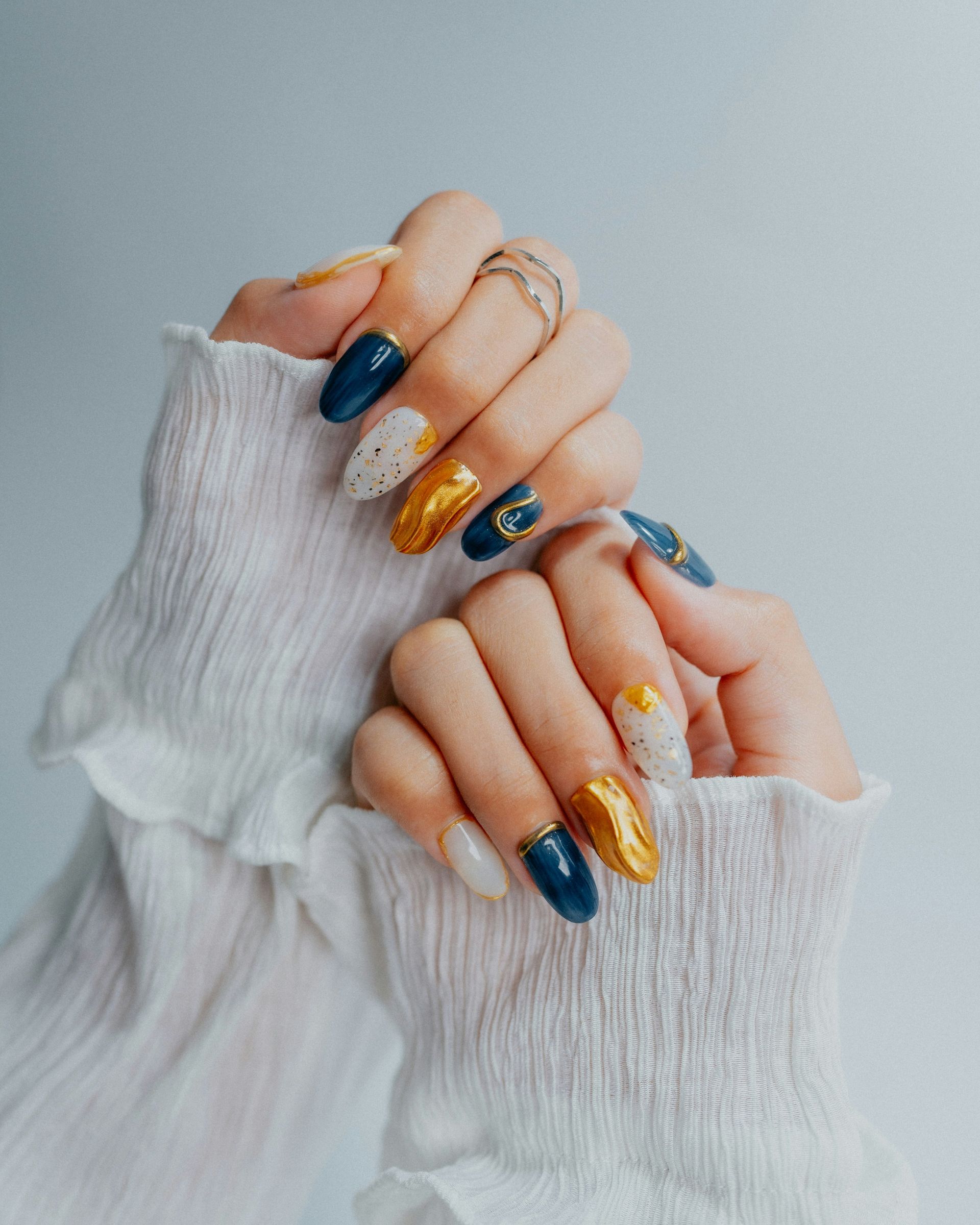 Woman's hands with ornate navy, gold, and white nails