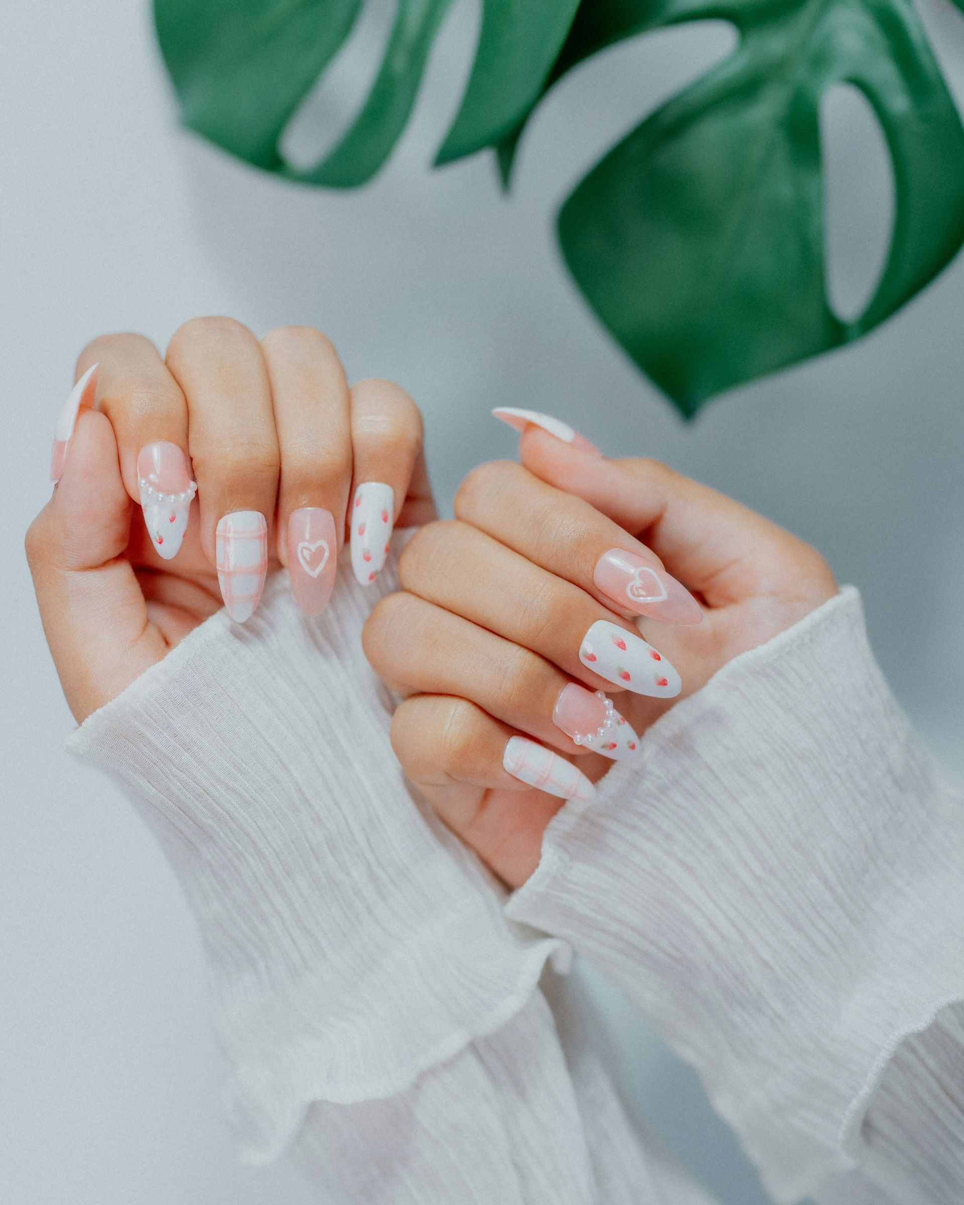 Woman's hands with white and pink heart-designed nails